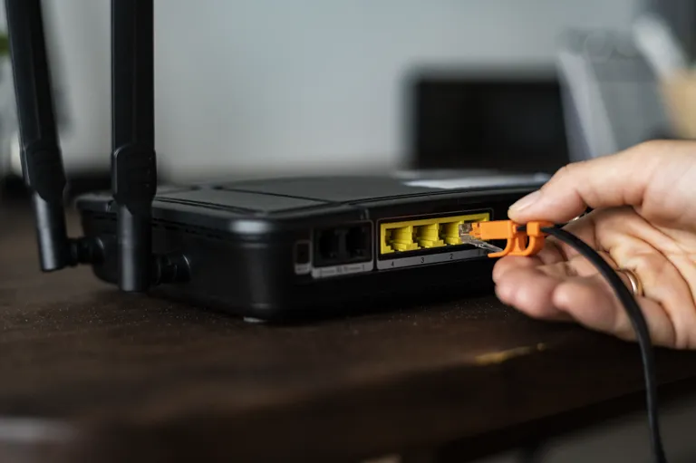 Dłoń podłączająca kabel Ethernet do portu routera bezprzewodowego