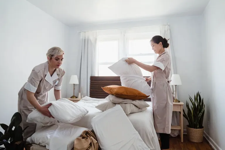 Pokojowe ścielą łóżko w pokoju hotelowym dla kolejnego gościa
