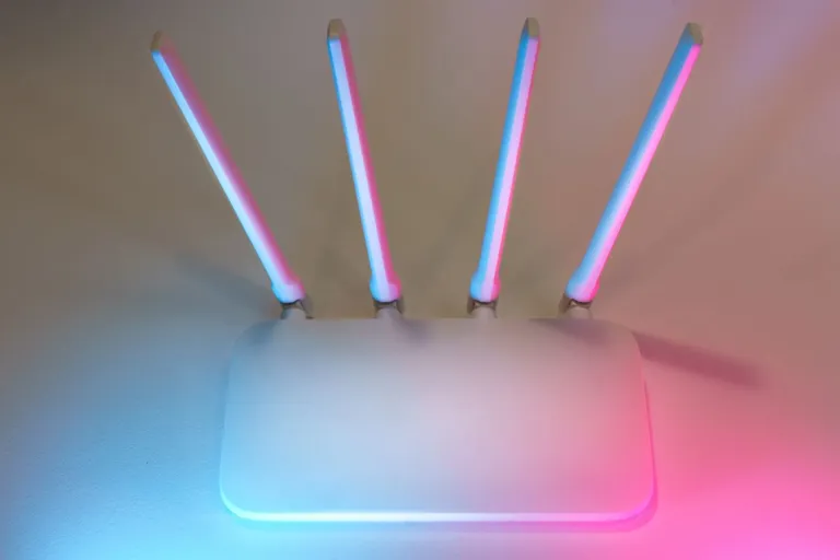 Biały router z czterema antenami przy podświetlonej ścianie