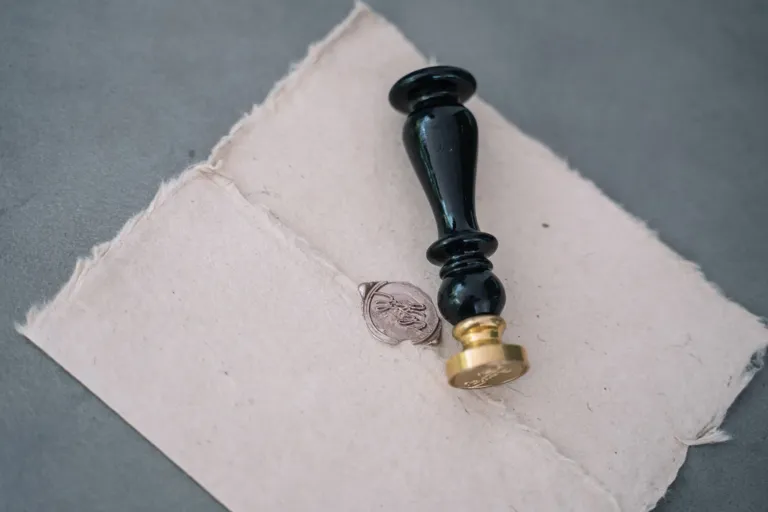 Odciśnięta pieczęć lakowa na arkuszu papieru, obok stempel