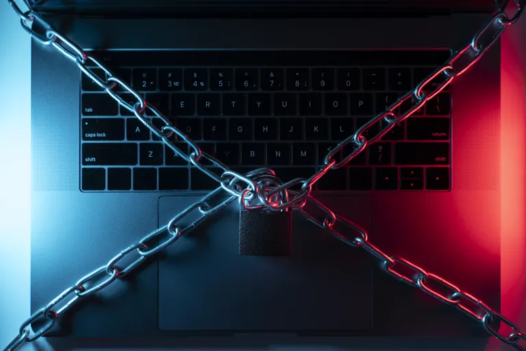 Laptop spięty łańcuchem z kłódką, symbol zablokowanych przez przestępców danych