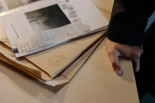 Wycinek z gazety spięty klipsem obok dwóch brązowych kopert na biurku