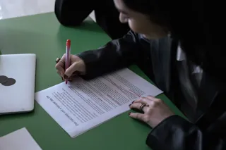 Osoba nanosi czerwonym długopisem poprawki na wydrukowanym tekście
