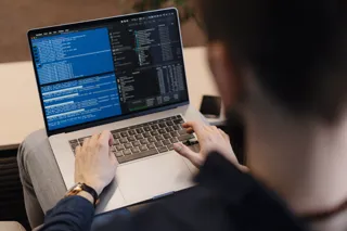 Programista piszący kod na laptopie, zbliżenie na ekran z kodem