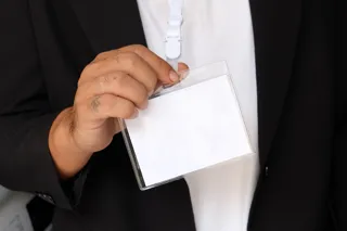 Osoba w eleganckim stroju trzyma na smyczy pusty identyfikator