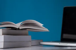 Laptop i książki w bibliotece, symbol firmowej bazy wiedzy